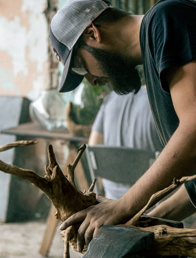 Gabriel trabajando una raíz de madera recuperada.