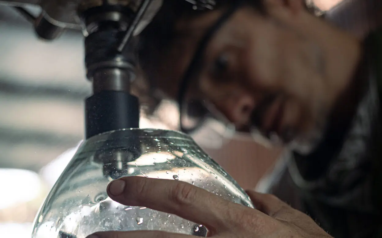 Un artesano revisando con los dedos el grosor de una pieza de vidrio.