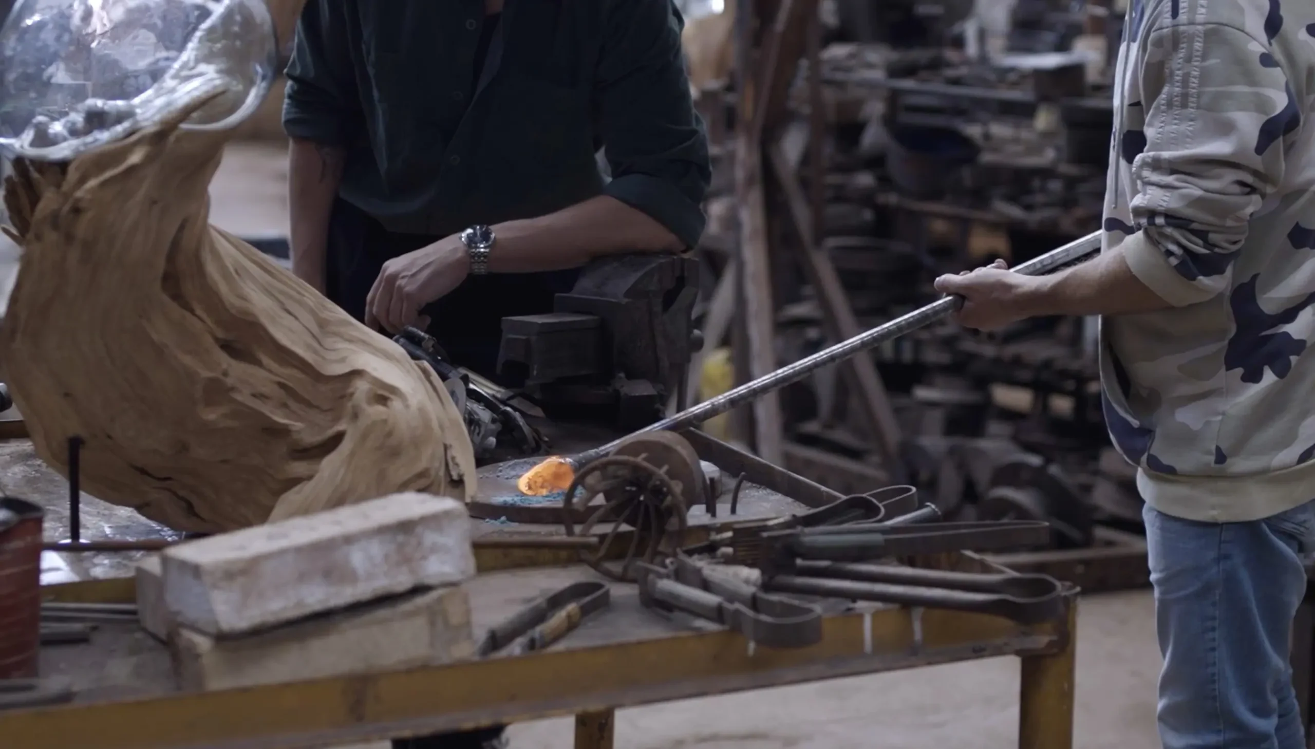 Dos artesanos trabajando el vidrio y el metal en el taller.